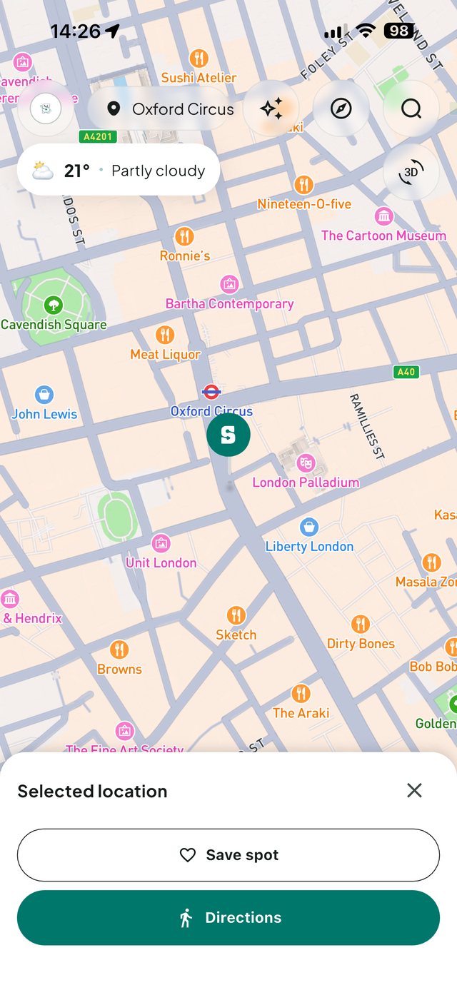 Screenshot of the Sentra app: a street map around Oxford Circus with a marker on your position, pins on nearby restaurants, shops and galleries, the Oxford Circus Underground roundel, a chip reading 21 degrees and partly cloudy, and a card at the bottom offering to save the selected spot or get directions.